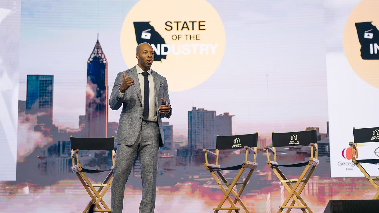 Man giving a presentation on a stage with 'State of the Industry' backdrop